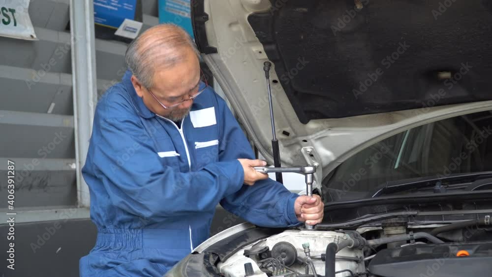 asian mechanic senior man using socket spanner wrench repairing a car in workshop at auto car repair service center. car engineer old man inspection vehicle details asian mechanic senior man using socket spanner wrench repairing a car in workshop at auto car repair service center. car engineer old man inspection vehicle details