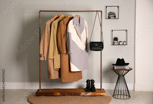 Different warm coats on rack in stylish room interior photo