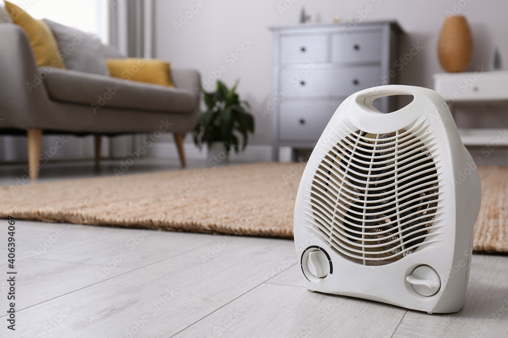 Modern electric fan heater on floor at home. Space for text Modern electric fan heater on floor at home. Space for text