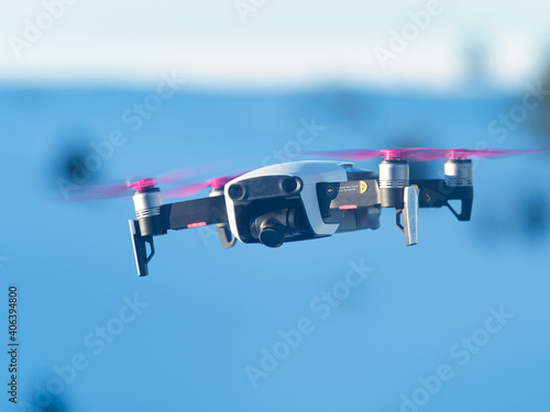 A drone with camera during the flight while filming and behind the blue sky