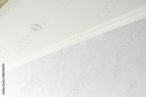 White ceiling with a white plinth in a room with gray painted walls. Decoration of the corner between the ceiling and the wall in the room. Ceiling molding in the interior. Detail of corner.