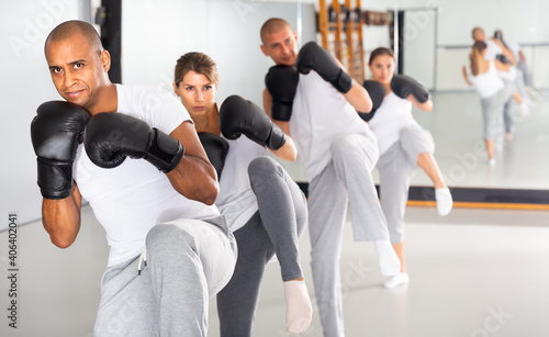Young hispanic male wearing boxing gloves in group workout time in self-defense in gym