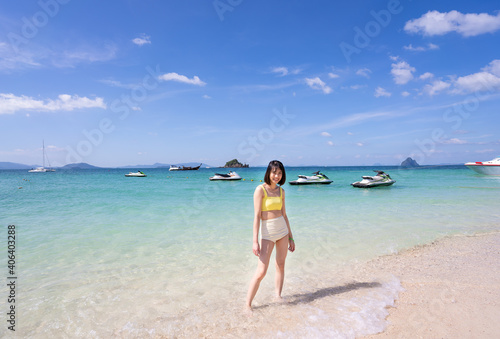Close up summer portrait of young Asian woman in yellow bikini on tropical beach. Holliday summer concept