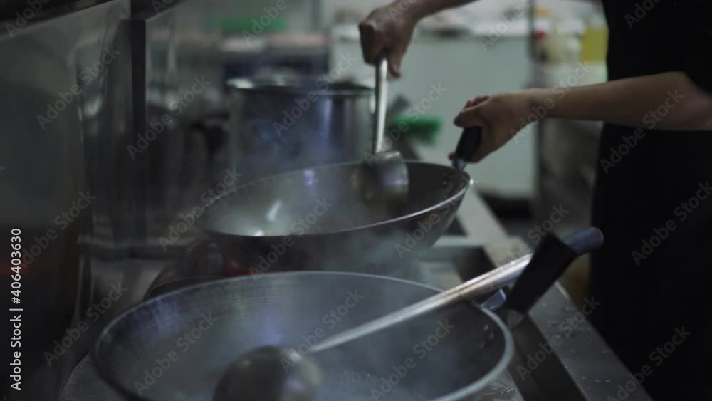 Chef Tossing And Stirring Ingredients Over High Heat In Kitchen Restaurant. - close up Chef Tossing And Stirring Ingredients Over High Heat In Kitchen Restaurant. - close up