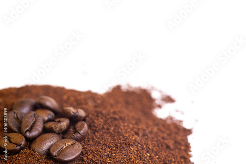Roasted coffee beans at the top of a pile of ground coffee on an isolated white background. With white area for copy space text.