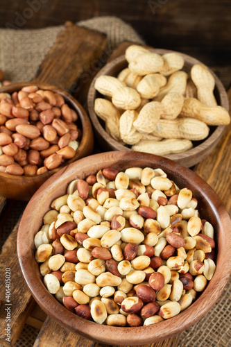 Roasted, raw peanuts and shelled in wooden bowls on a brown wooden table