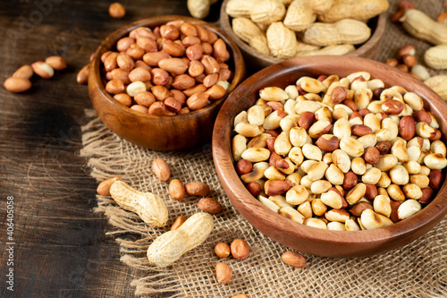 Roasted, raw peanuts and shelled in wooden bowls on a brown wooden table