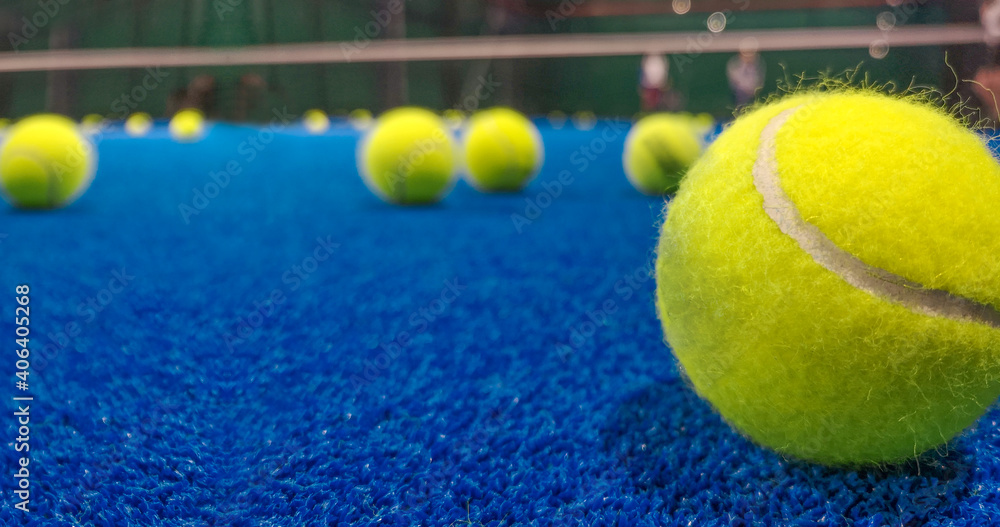 Padel ball on the blue synthetic court on blurried background