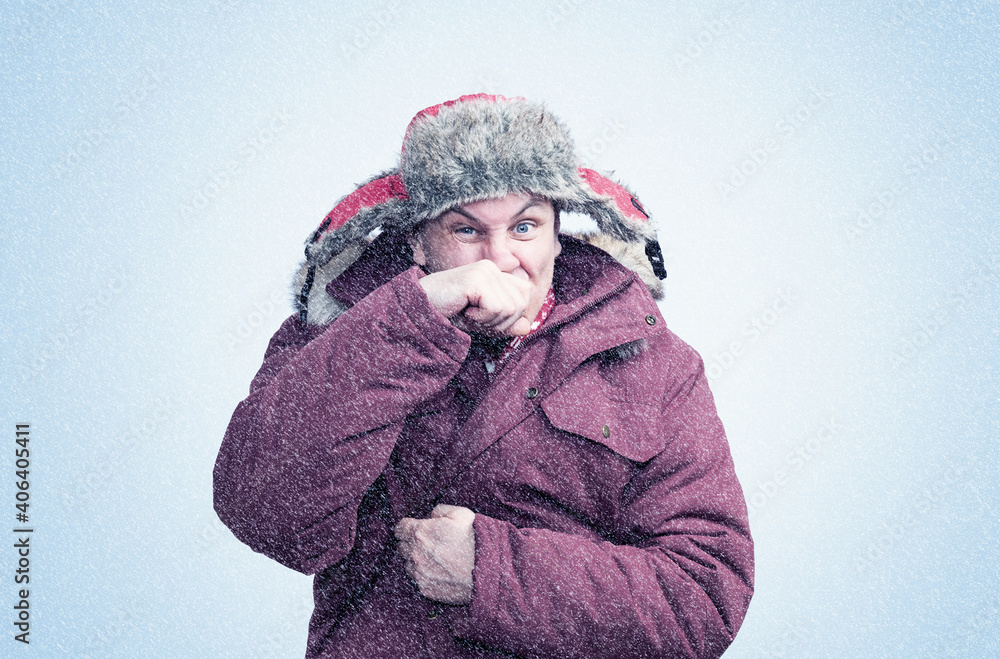 A man in red winter clothes wipes his nose with his hand in the cold, snow is falling around A man in red winter clothes wipes his nose with his hand in the cold, snow is falling around
