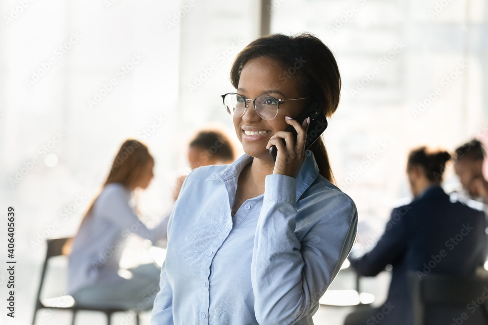 Smiling young African American woman employee talk on smartphone with client or business partner. Happy ethnic businesswoman have cellphone call use good mobile provider services. Technology concept. Smiling young African American woman employee talk on smartphone with client or business partner. Happy ethnic businesswoman have cellphone call use good mobile provider services. Technology concept.