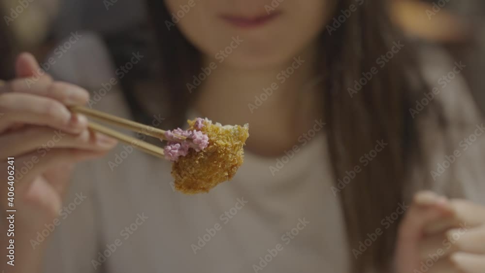 Woman eating fried oyster in slow motion, blurred background