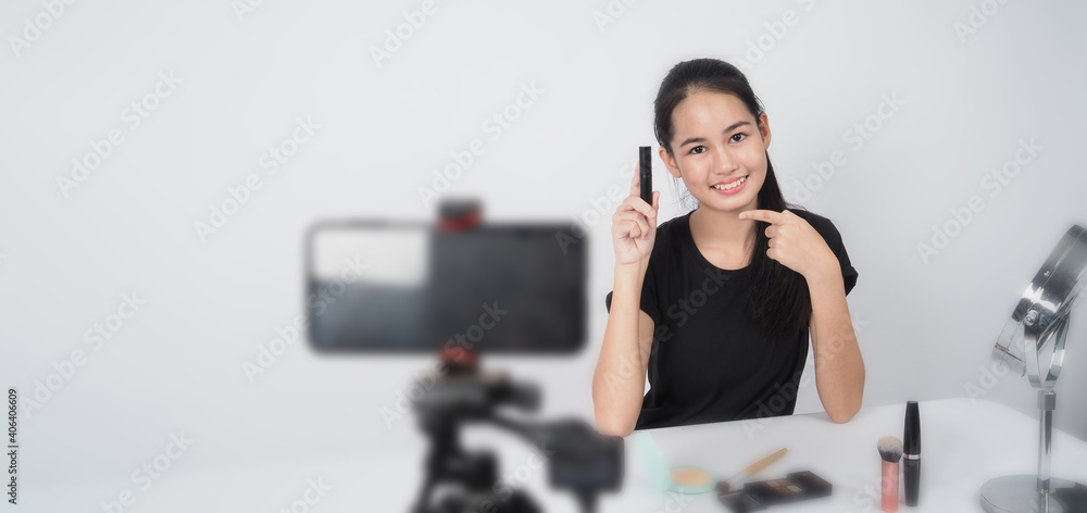 Beauty Blogger. Asian teen woman sit in front of camera and live broadcasting as a beauty blogger influencer or youtuber to review or advice about how to make up at home. studio shot white background. Beauty Blogger. Asian teen woman sit in front of camera and live broadcasting as a beauty blogger influencer or youtuber to review or advice about how to make up at home. studio shot white background.