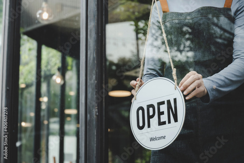 asian waitress staff woman wearing apron turning open sign board on glass door in modern cafe coffee shop, hotel, cafe restaurant, retail store, small business owner, food and drink concept