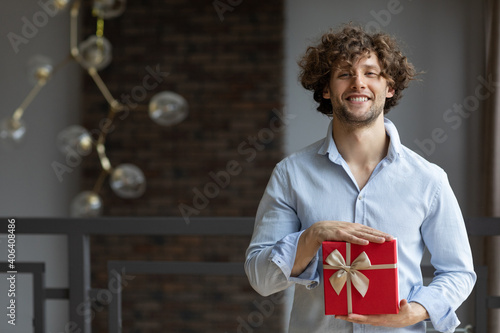 Portrait attractive casual man with present box and looking at camera
