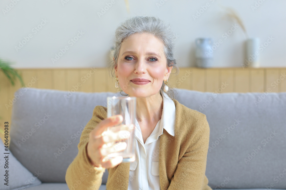 Attractive middle aged woman holding glass of water and looking at camera. Healthy lifestyle. Attractive middle aged woman holding glass of water and looking at camera. Healthy lifestyle.
