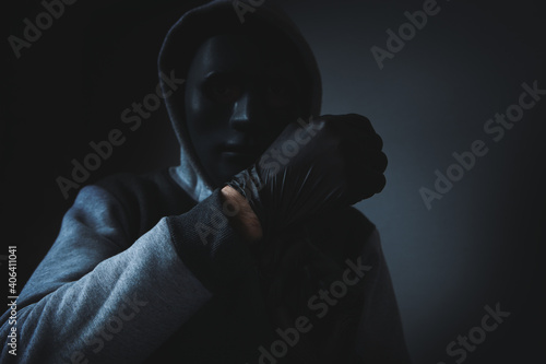 man with hood and face mask puts on black gloves photo