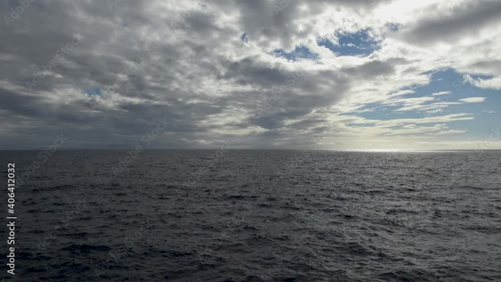 Wide, static shot of ocean and cloudy sky