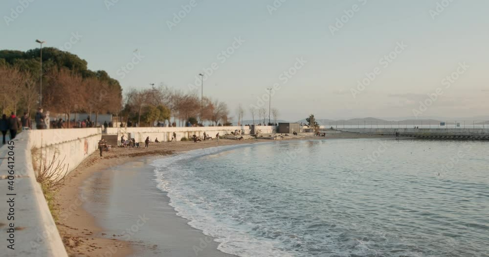 Timelapse of Blue Sea Waves Crashing on the Sand Shore while Crowded People are Walking on Sunny Day with Open Sky Timelapse of Blue Sea Waves Crashing on the Sand Shore while Crowded People are Walking on Sunny Day with Open Sky