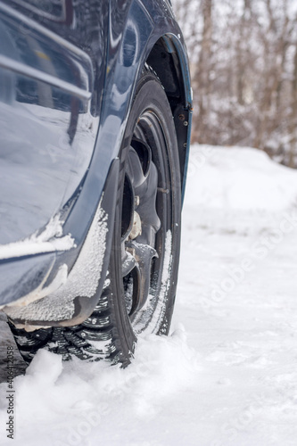Close up of the front left car wheel on the snow. Concept - Care must be taken when driving on slippery, snowy roads. Vertical photo.