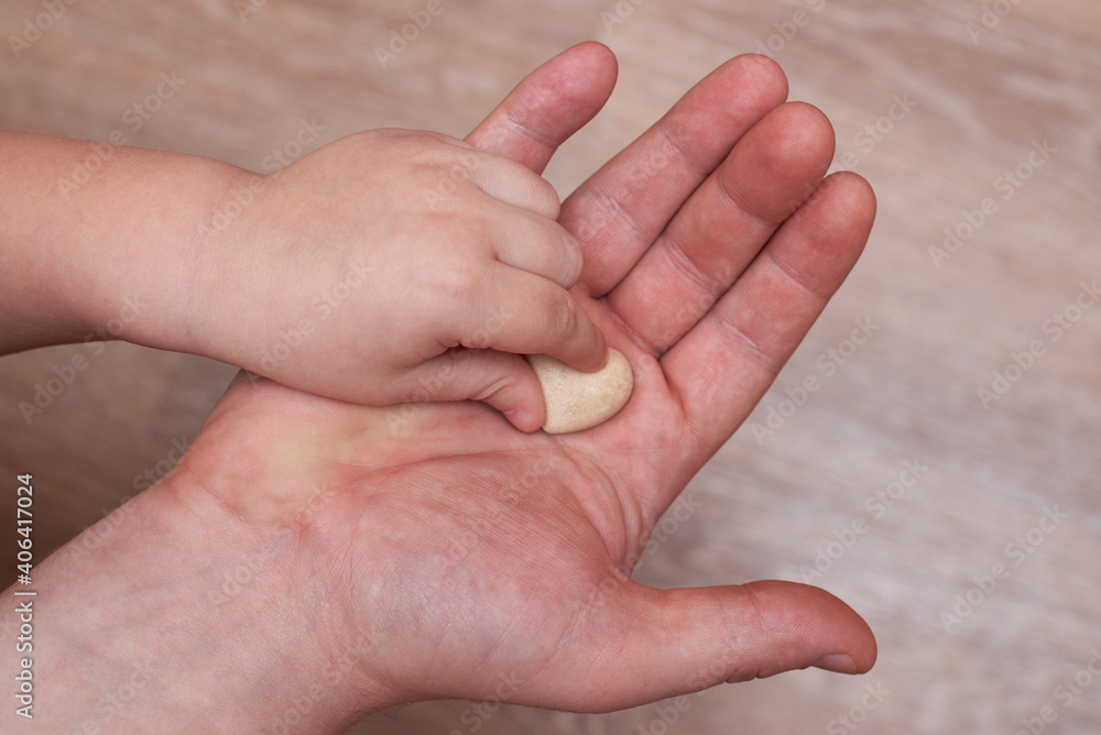 The little son puts a small plaster heart in his dad's hand. The little son puts a small plaster heart in his dad's hand.