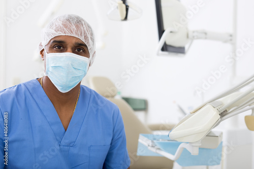 Portrait of professional hispanic stomatologist posing in dental clinic, confidently looking at camera