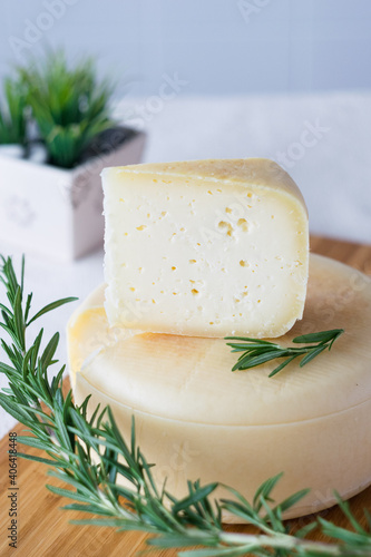 A head with a slice of classic Italian cheese Caciotta made from natural cow's milk on cutting board, selective focus