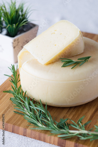 A head with a slice of classic Italian cheese Caciotta made from natural cow's milk on cutting board, selective focus