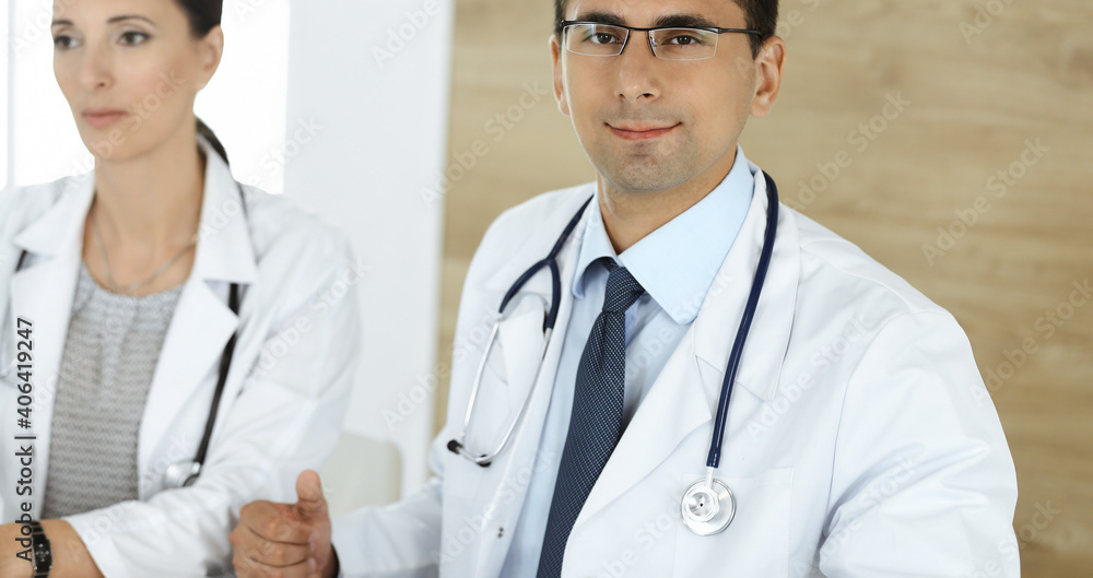 Fototapeta premium Two doctors discussing treatment problems while sitting at the desk in hospital office. Data in medicine and health care concept