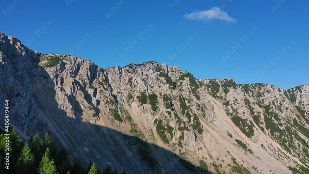 Aerial reveal shot of Petzen mountain peak and the forest nearby Aerial reveal shot of Petzen mountain peak and the forest nearby