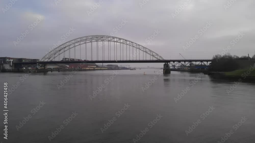 Calm river streaming slowly below a bascule bridge where cars are driving over. Steady dolly drone shot Calm river streaming slowly below a bascule bridge where cars are driving over. Steady dolly drone shot
