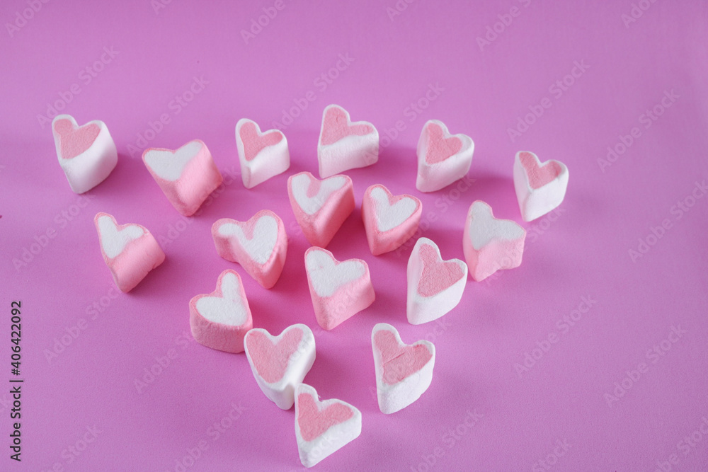 Top view of heart shape marshmallows on pink background 