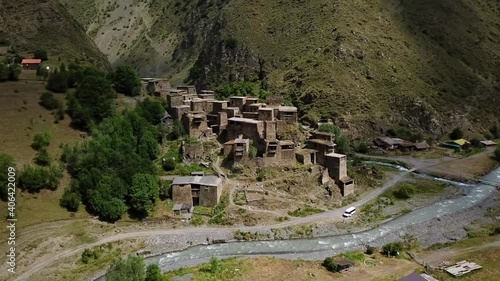 Shatili small town settlement ruins at bottom of greater Caucasus mountains winding river aerial slow push in photo