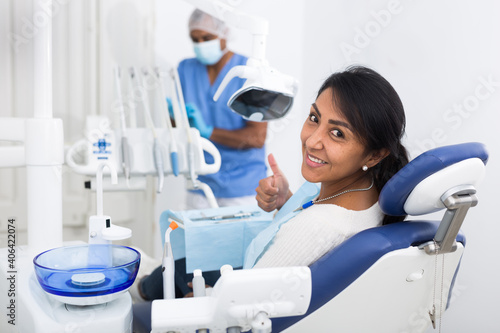 Portrait of satisfied woman visiting dentist giving thumbs up in the dental clinic