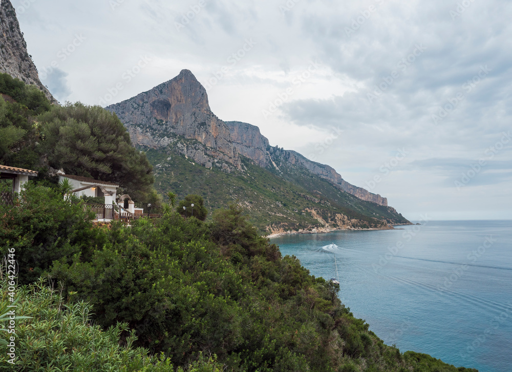 View over Gulf of Orosei from Pedra longa with limestone cliffs, green bushes, restaurante house and turquoise blue water. Famous travel touristic destination in Sardinia island, Italy.