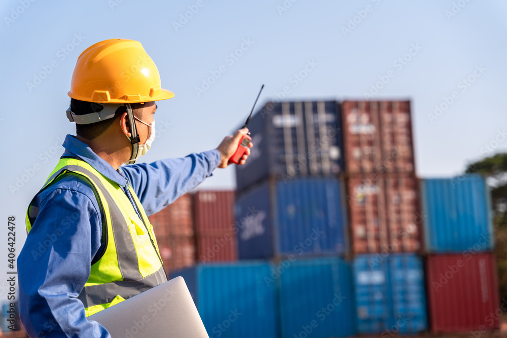 foreman worker wear a mask working use a long distance radio control container cargo harbor to loading containers. Logistics import export shipping concept. foreman worker wear a mask working use a long distance radio control container cargo harbor to loading containers. Logistics import export shipping concept.
