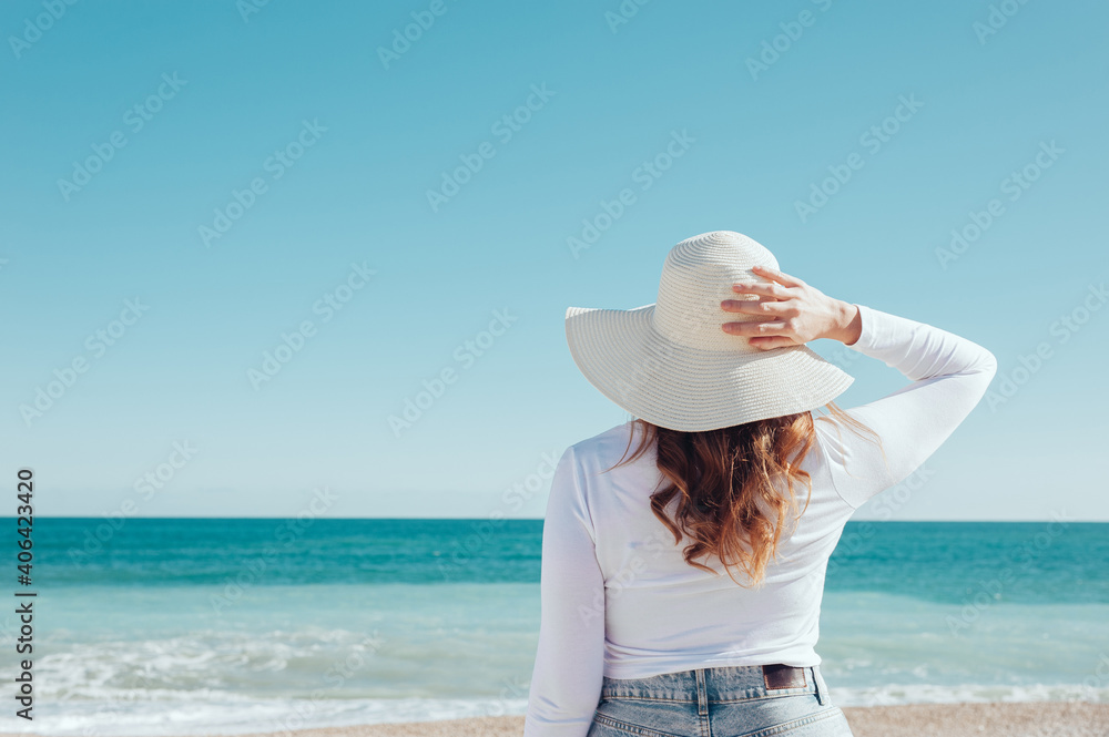 Woman wearing a hat looking at the sea