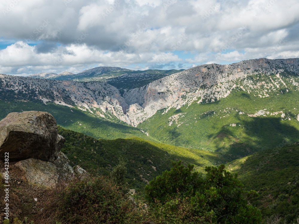 Naklejka premium View of Gola Su Gorropu gorge, famous hiking destinantion at green forest landscape of Supramonte Mountains with limestone rock and mediterranean vegetation, Nuoro, Sardinia, Italy. Summer cloudy day