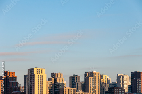 Sunlit roofs of high-rise buildings, blue sky, place for an inscription