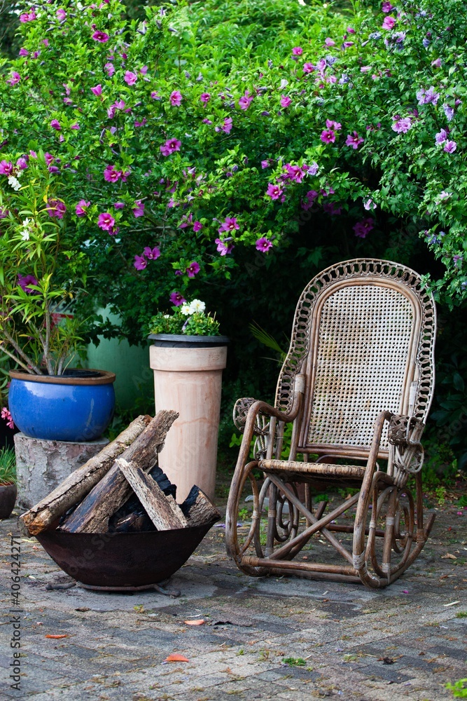 rocking chair and fire pit on garden patio with flowers