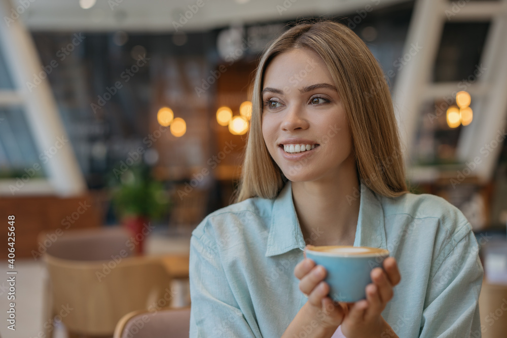 Close up portrait of beautiful smiling woman drinking coffee in cafe. Happy female holding cup with hot drink. Coffee break concept Close up portrait of beautiful smiling woman drinking coffee in cafe. Happy female holding cup with hot drink. Coffee break concept
