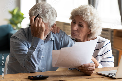 Worried middle aged woman supporting frustrated old senior husband, calculating domestic expenses together at home, feeling depressed having financial problems, bankruptcy banking debt concept.