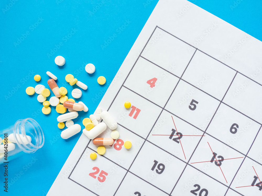 The medicinal tablets were poured out of the bottle. Placed next to a calendar to tell the time Put on a blue background.. The medicinal tablets were poured out of the bottle. Placed next to a calendar to tell the time Put on a blue background..