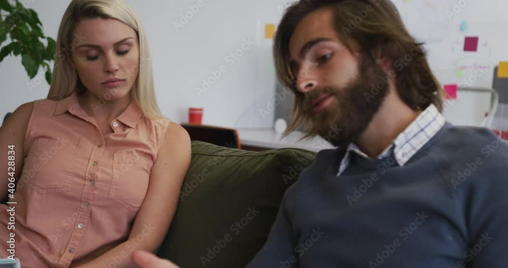 Caucasian business people sitting on couch going through paperwork in modern office Caucasian business people sitting on couch going through paperwork in modern office
