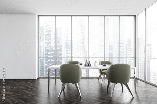 White dining table and green chairs near window with city view
