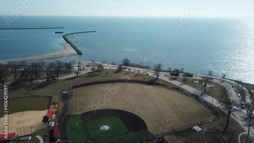 Aerial view descending above baseball field and revealing stunning coastline overlooking Long Island Sound on a sunny day in Bridgeport, Connecticut, USA. photo