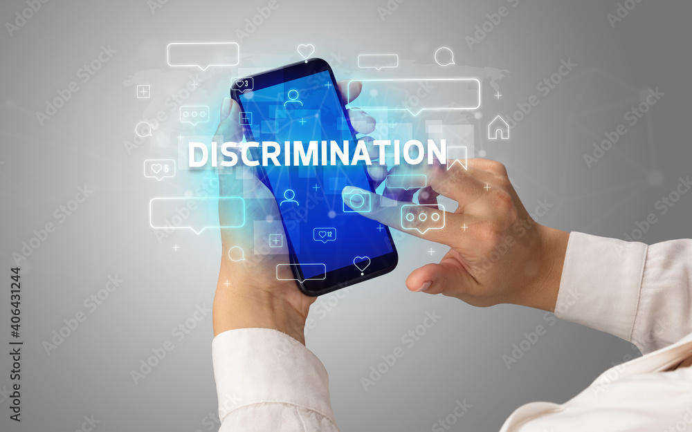 Female hand typing on smartphone with DISCRIMINATION inscription, social media concept Female hand typing on smartphone with DISCRIMINATION inscription, social media concept