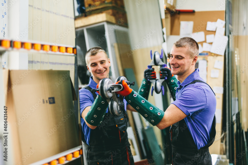 Glazier worker holding a big mirror glass pane in workshop. Industry Glazier worker holding a big mirror glass pane in workshop. Industry
