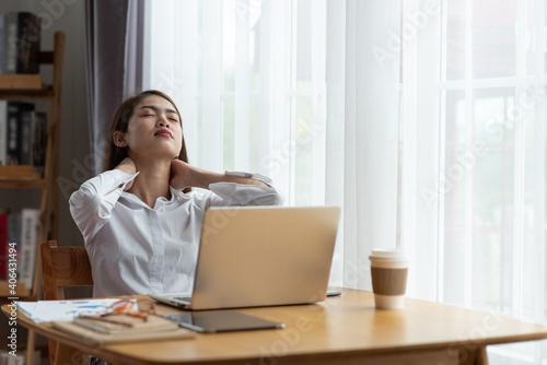 Young businesswoman is having pain in neck at work
