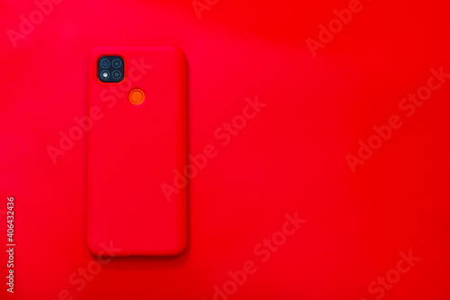 Red smartphone in a silicone case with four cameras and a fingerprint scanner on a red background.