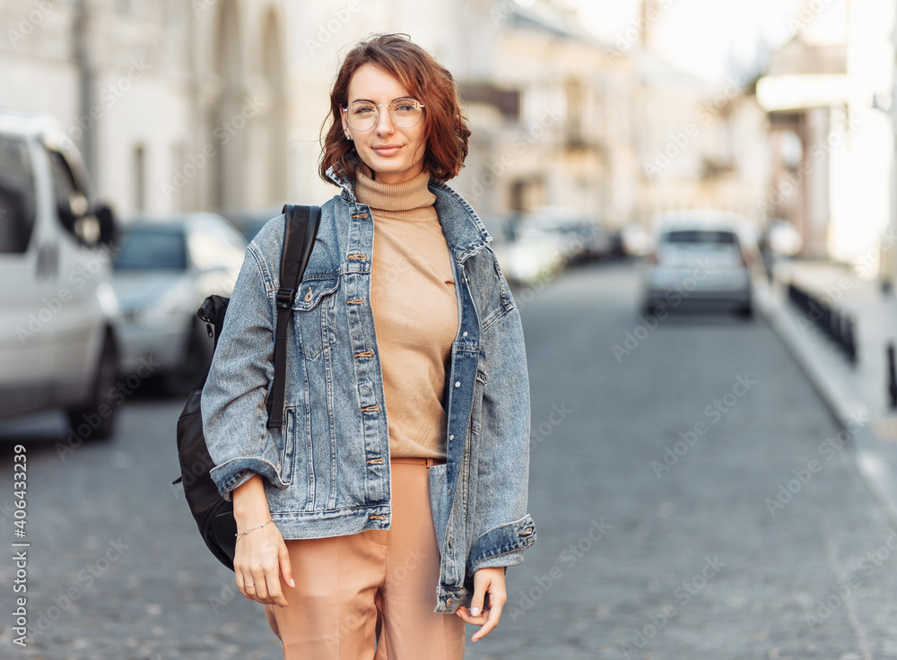 Stylish attractive woman in denim jacket on urban street